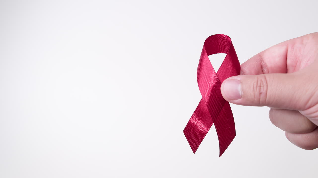 деталь мужской руки, надевающей ленту красного цвета на белом фоне