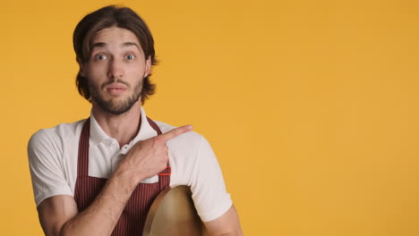 caucasian waiter in front of camera on yellow background.