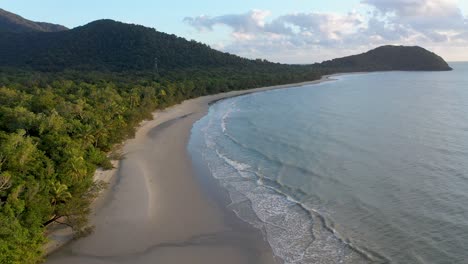 Cape-Tribulation-backward-aerial-of-palm-trees-and-ocean-on-overcast-day,-Daintree-Rainforest,-Queensland,-Australia