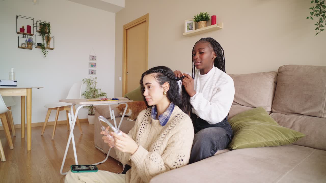 Two women braiding hair at home