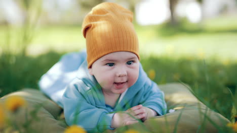 half a year old toddler looks around with interest. adorable child resting on the mattress outside in the nature.