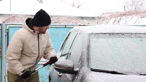 hombre raspando la escarcha de la ventana del auto durante el invierno