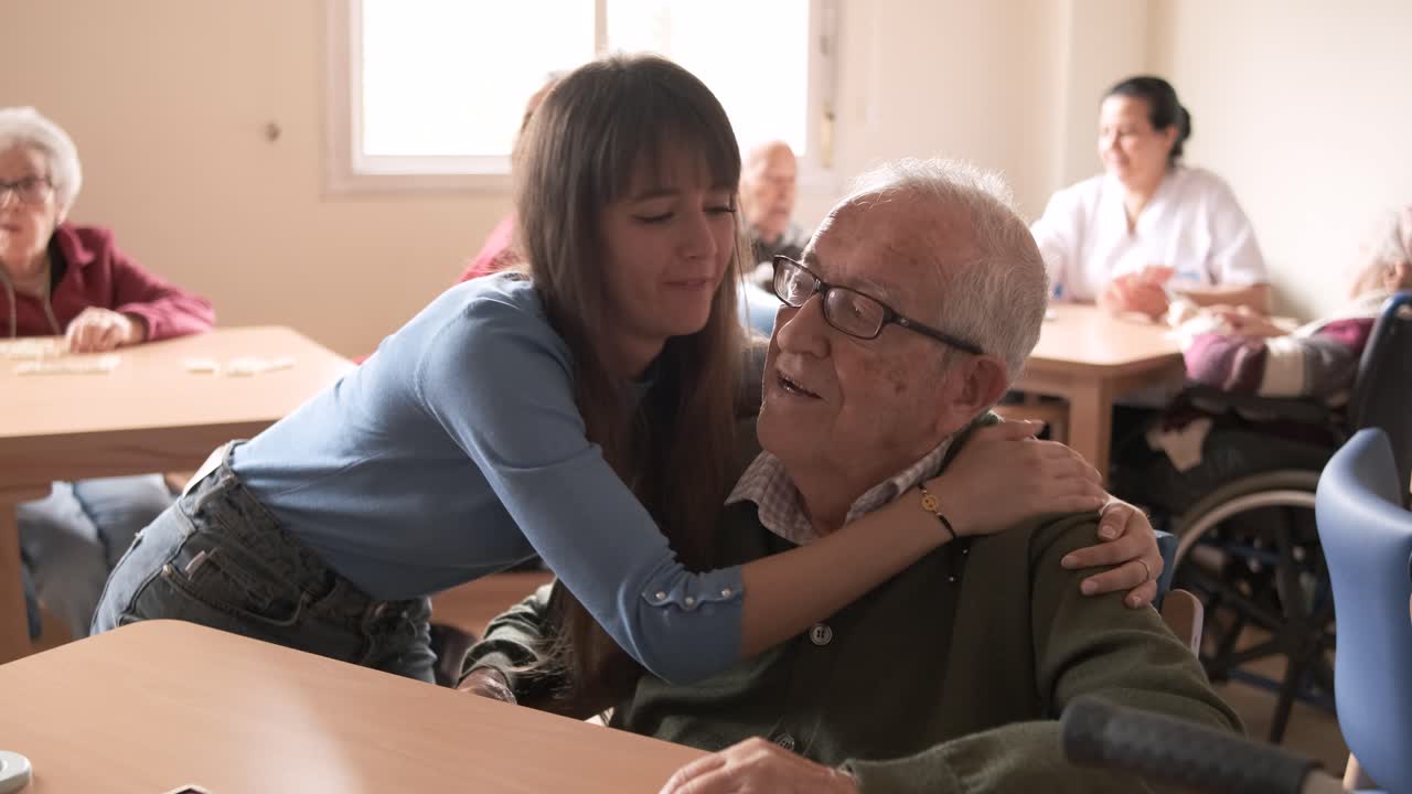 Smiling young woman hugging elderly man in retirement home
