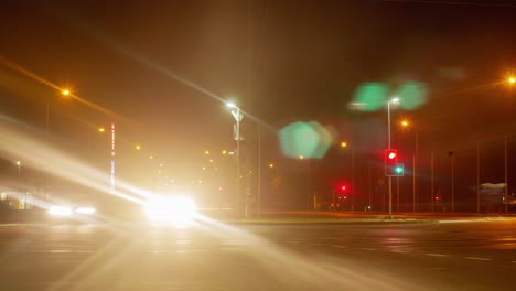 timelapse of city rush hour traffic on the street of liepaja, traffic light streaks, glowing city lights through the mist, low wide shot