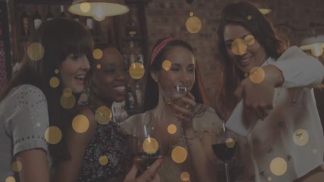 Animation-of-glowing-yellow-lights-over-smiling-female-friends-at-party-taking-selfies