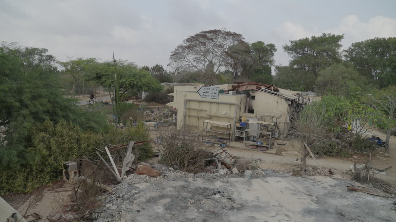 On top of destroyed home in Kibbutz Nir Oz after Hamas Attack, Gush Katif sign