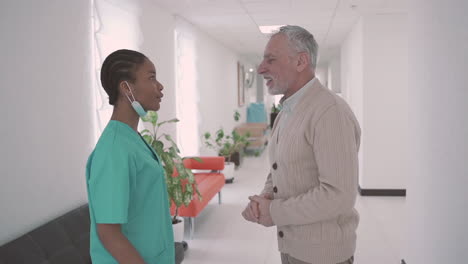 Young-Female-Doctor-Talks-To-An-Old-Man-Patient-With-A-Beard-And-Gray-Hair-In-The-Hospital