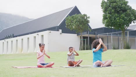 video of diverse schoolgirls and schoolboy practicing yoga meditation in outdoor class, copy space