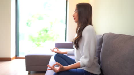 Mujer-Exótica-Practicando-Yoga-En-La-Comodidad-De-La-Sala-De-Estar,-Pose-Fácil-Aka-Sukhasana,-Gesto-De-Dedo-Gyan-Mudra,-Cámara-Lenta-De-Cuadro-Completo