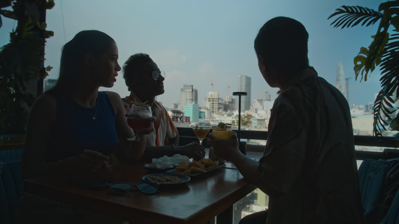 Low-key of Three Friends Sitting by Panoramic Window at Restaurant