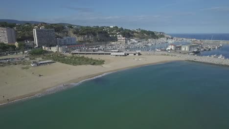 coast view over a small town port and beach, aerial pull away shot