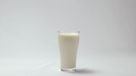 Leckerer-Schokoladenkeks,-Der-In-Ein-Glas-Mit-Milch-Fällt,-Weißer-Hintergrund-4k