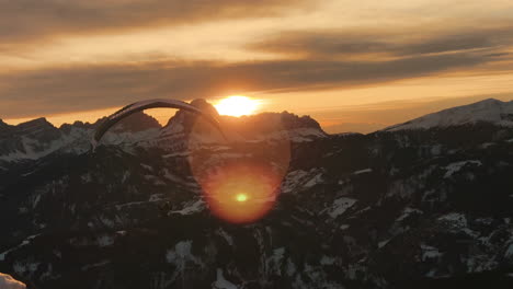 paragliding over snowy alps at sunset