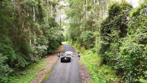 drone flying over a forest road with a car