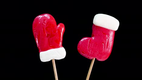 el caramelo de año nuevo está girando, el guante de santa claus, los calcetines o las botas de santa claus. caramelo sobre un fondo negro