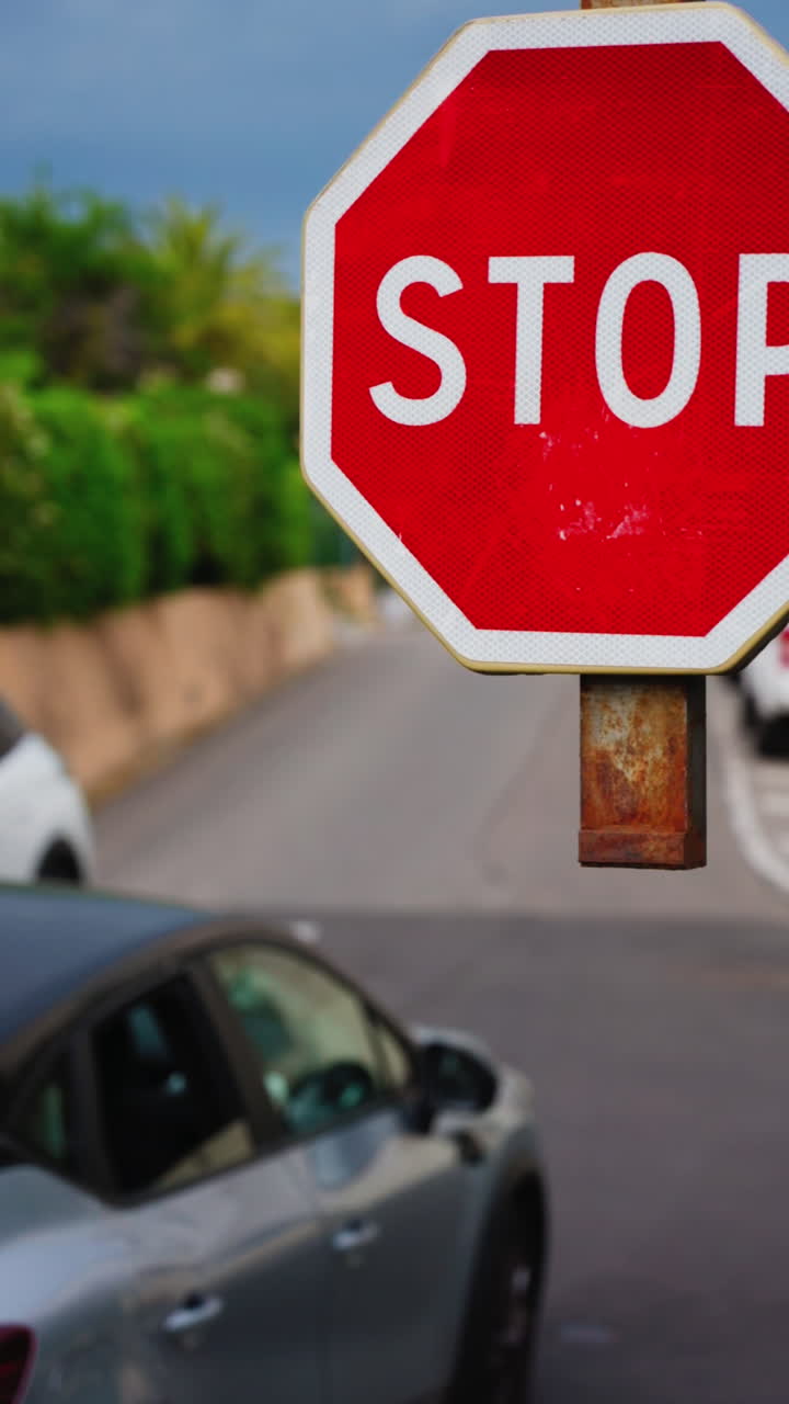 Close up of a stop sign with a blurred background of cars moving on the street. Vertical