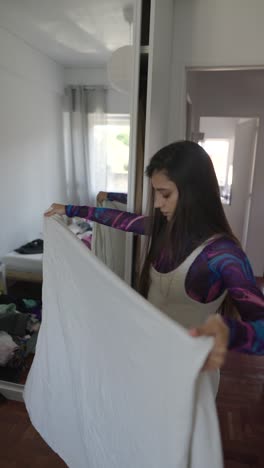 woman folding laundry in a bedroom