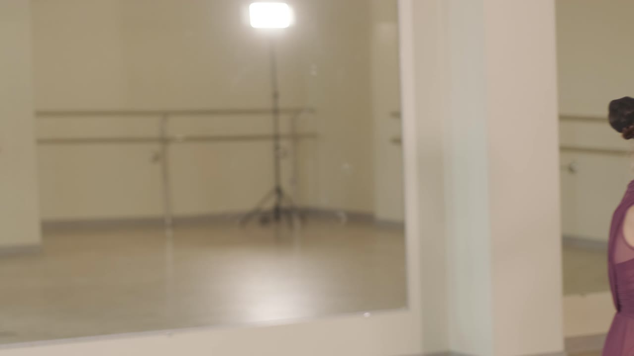 un grupo de jóvenes estudiantes de ballet con ropa de baile negra practicando posiciones en un amplio estudio de ballet con pisos de madera y barras montadas en la pared. expresiones enfocadas y movimientos sincronizados.