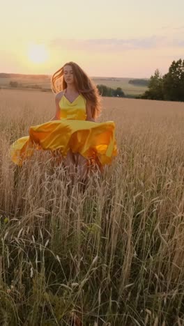 young woman in yellow dress twirling in golden wheat field during sunset with warm glow