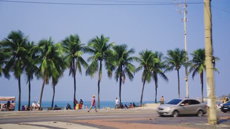 sunny day with palms, tourists, cars on ipanema beach in rio de janeiro, brazil
