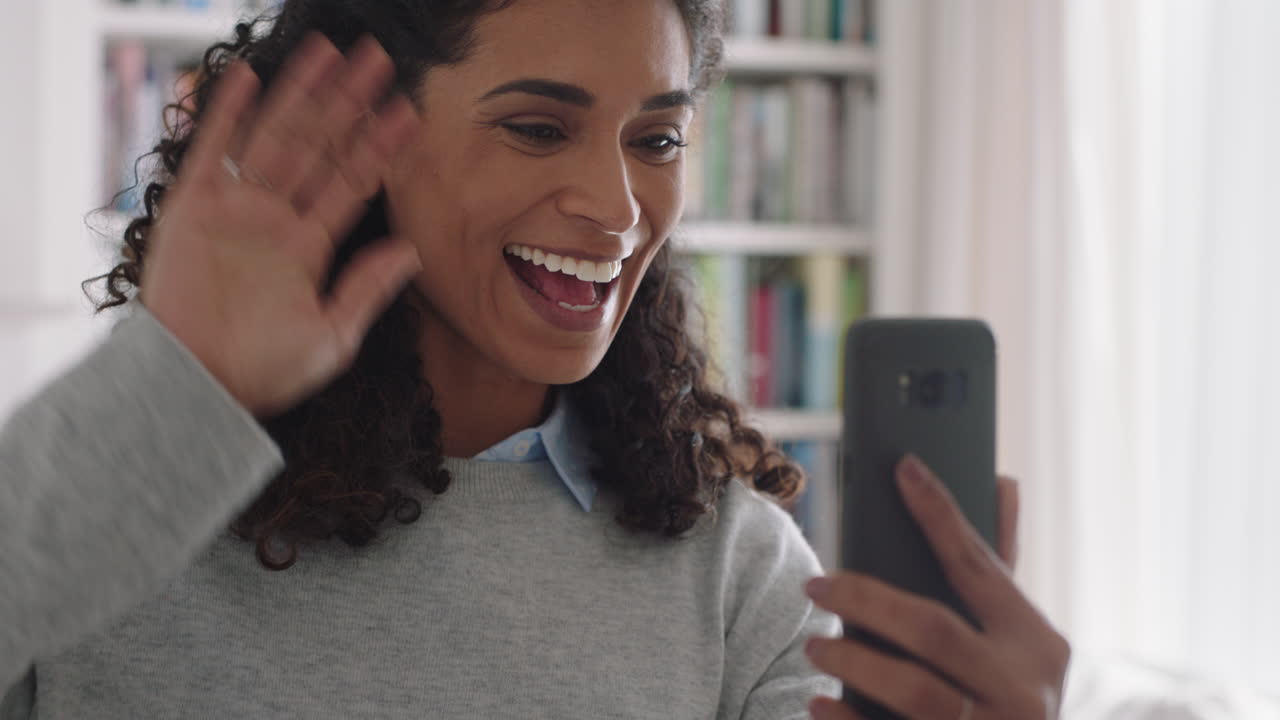 feliz mujer de raza mixta teniendo chat de video usando teléfono inteligente saludando a bebé sonriendo disfrutando de charlar en el teléfono móvil en casa 4k imágenes