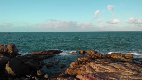 Aerial-view-over-rocks-and-calm-water,-golden-hour-in-Bowen,-Australia---reverse,-drone-shot