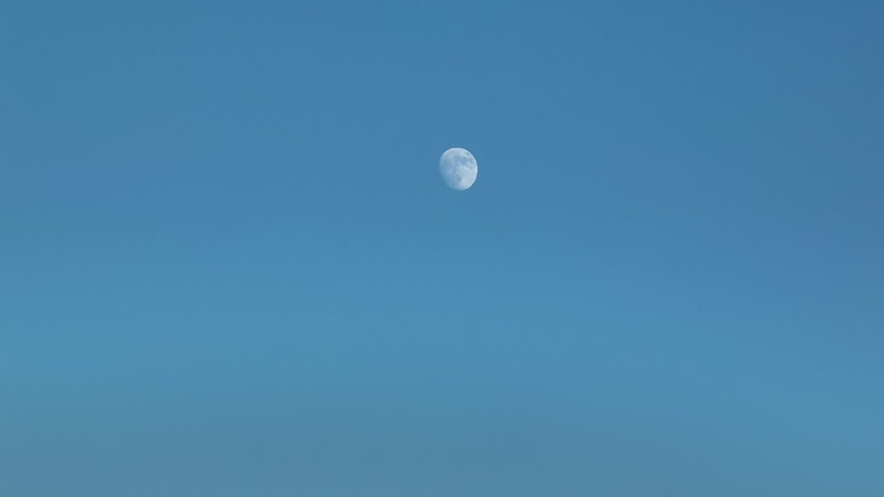 Waxing Gibbous Moon against blue sky time lapse