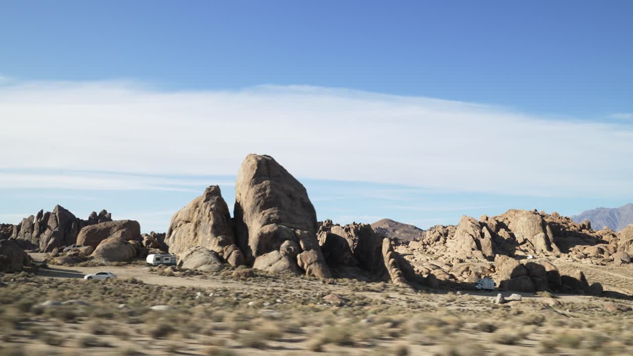 View from a moving car that is driving in desert with mountains in Alabama Hills on American road trip