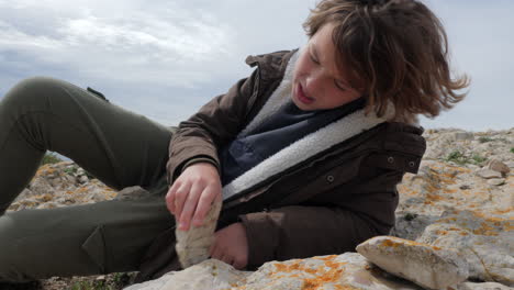 boy trying to break stone against rocky ground