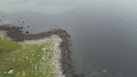 Schwenken-Sie-Den-Blick-Vom-Offenen-Meer-Auf-Den-Mit-Kieselsteinen-Bedeckten-Strand-Farstadsanden-Und-Enthüllen-Sie-Die-Grüne-Grasküstenlandschaft-In-Norwegen