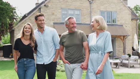 family with senior parents and adult offspring walking and talking in garden together