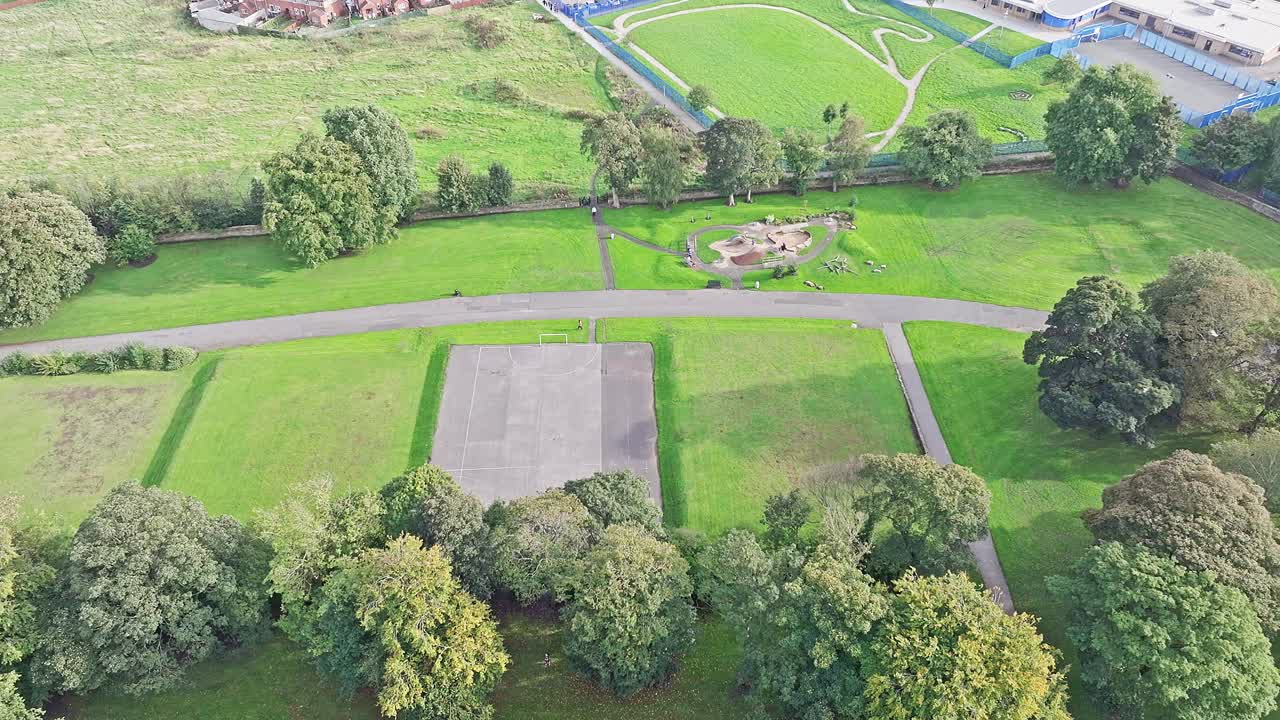 Sinking aerial of football pitch and green fields in Bradford, UK