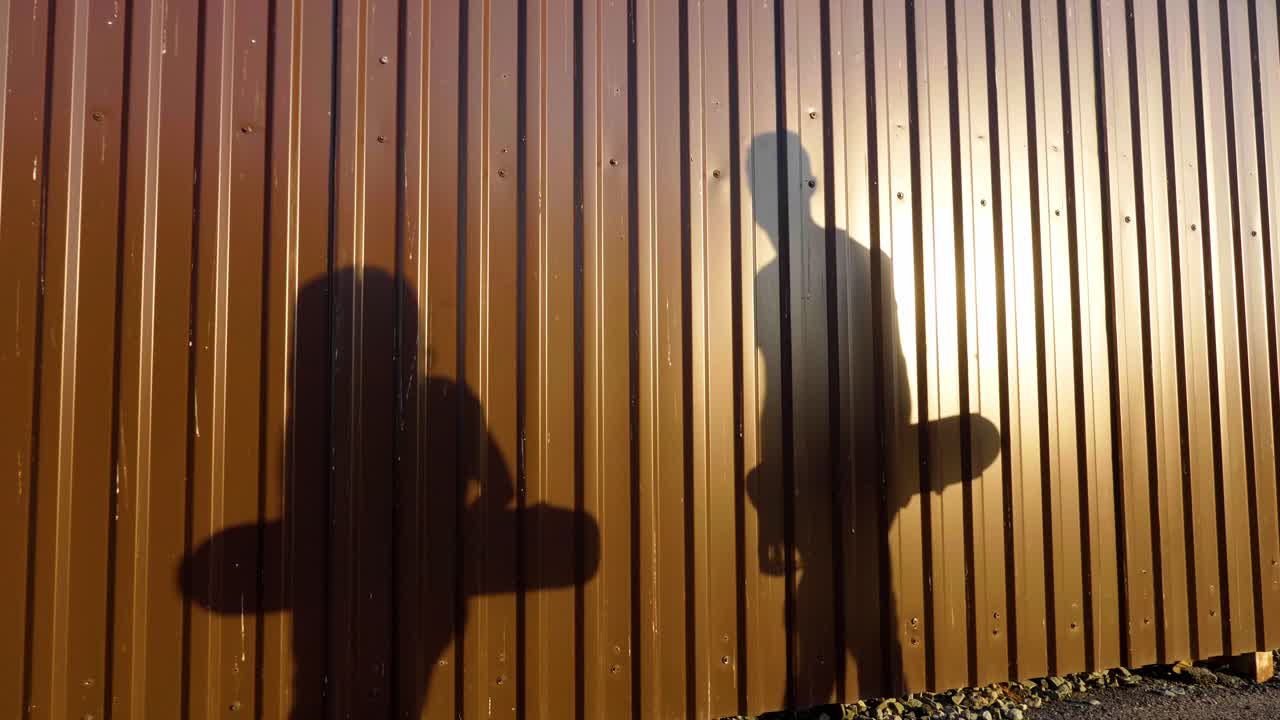 Shadows of Skateboarders by a Metal Wall