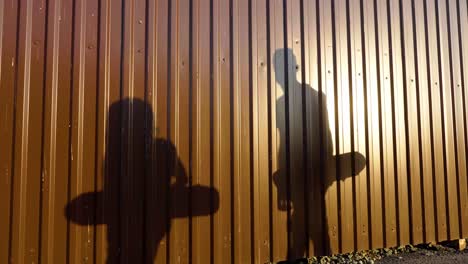 shadows of skateboarders by a metal wall