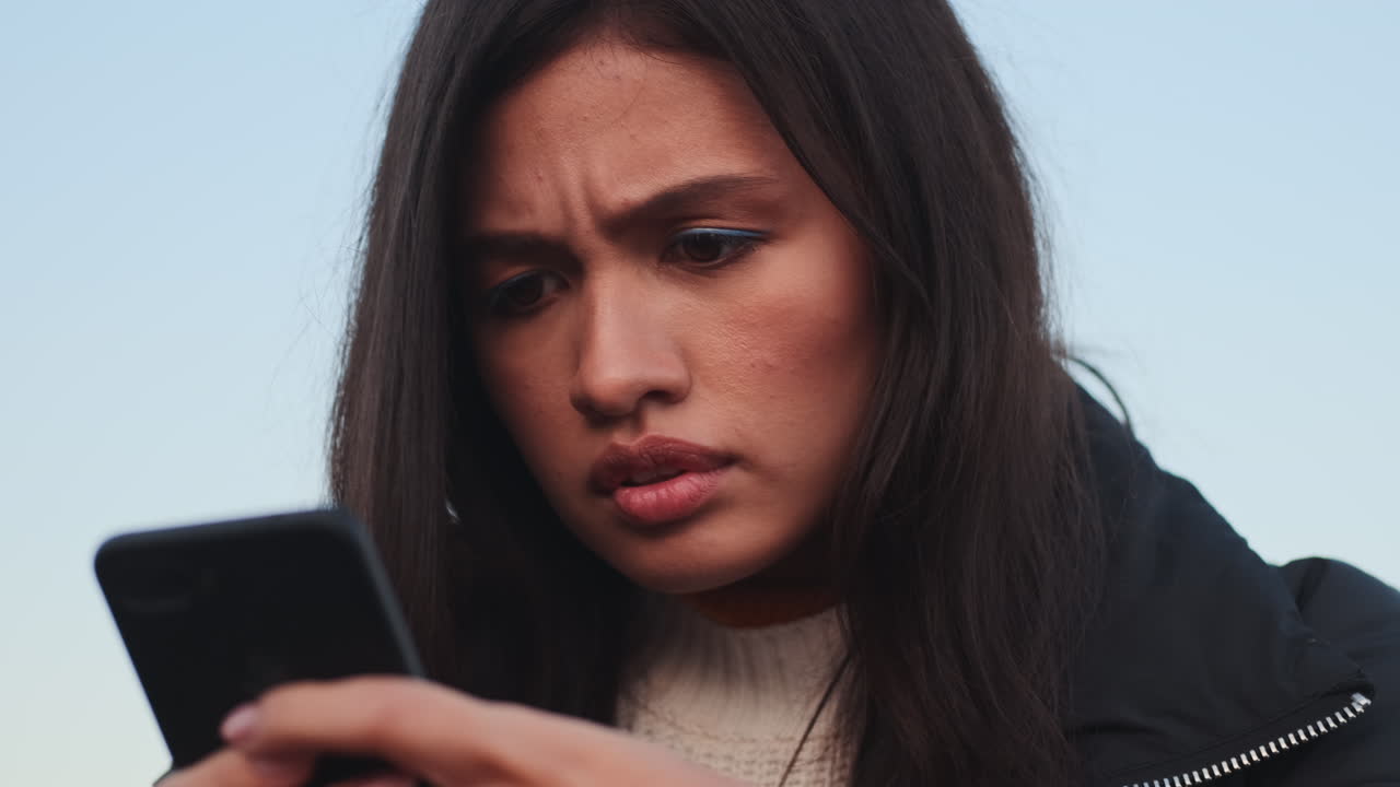 Menina asiática triste a usar telemóvel.