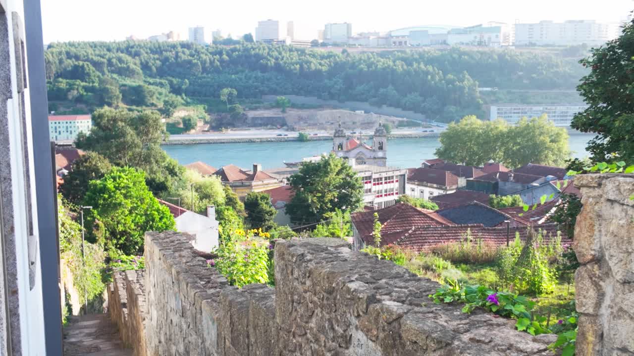 Narrow stone path between historic walls, descending toward Douro River in Porto