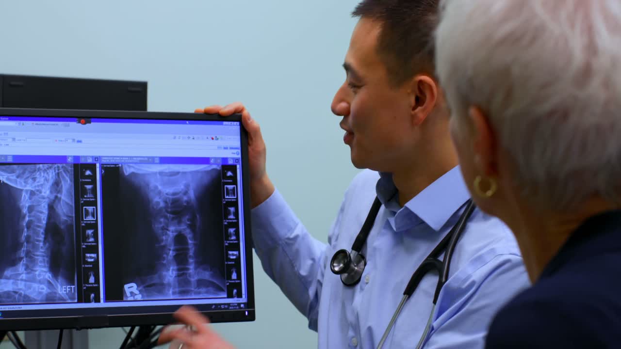 Young Asian male doctor discussing over x-ray report on computer at clinic 4k
