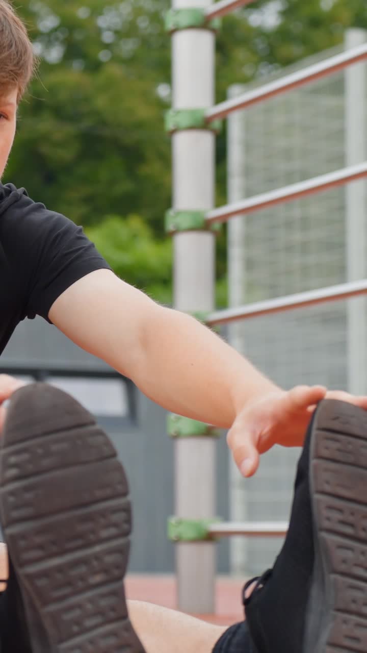 Young man stretching outdoors, preparing for a workout, focused mood, vertical