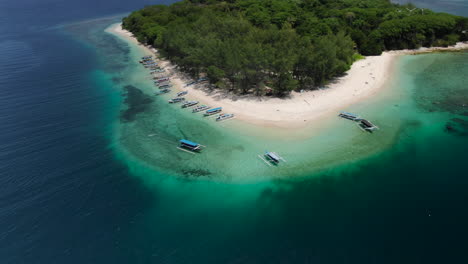 Toma-Orbital-Aérea-Sobre-Una-Isla-Tropical-En-El-Océano-Azul,-Turistas-Que-Visitan-Asia-En-Barcos-Tradicionales