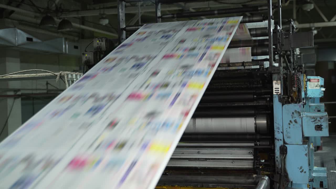 Color printing of newspapers on large machines, conveyor. Rolls of paper are drawn across the printing press. Printing house. Media, article, headline, daily news, print edition, journalism, politics