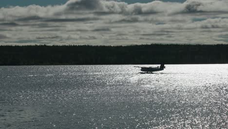 silhouette of float plane on sparkling lake preparing for takeoff.