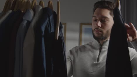 young man at home choosing business suit from wardrobe for job interview