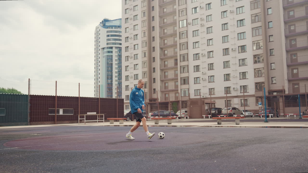 Male runner practicing alone outdoors, Athlete sprinting in city street during rain, Energetic male athlete performing dynamic soccer maneuver alone on rainy city sidewalk while focused