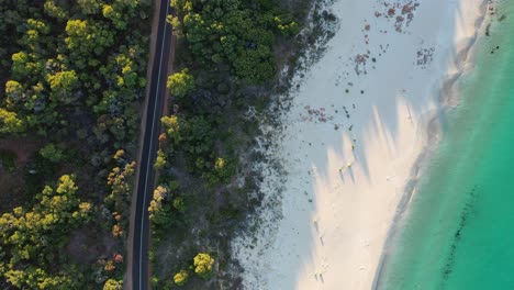 Una-Carretera-Costera-Vacía-Y-Una-Playa-Tropical-De-Arena-Blanca,-Vista-Aérea-De-Drones-De-Arriba-Hacia-Abajo