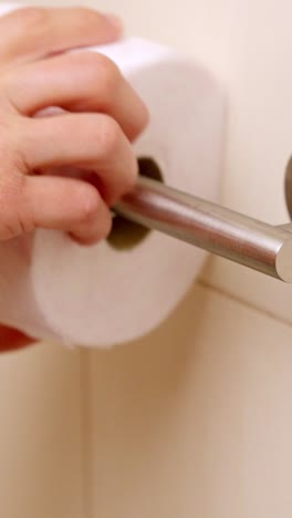 man replacing empty toilet paper roll in bathroom