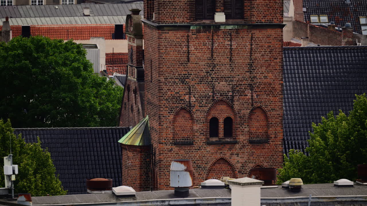 Torre di chiesa con orologio visibile sullo sfondo di edifici cittadini. Copenaghen, Danimarca