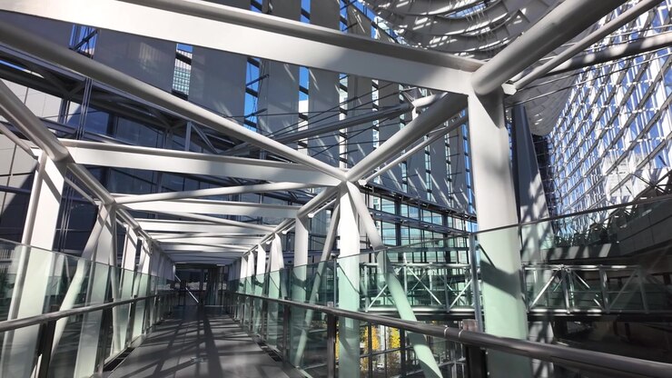 Passarela futurista dentro do edifício do Fórum Internacional de Tóquio, com vigas de metal e corrimãos de vidro