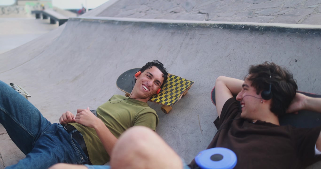 Giovani uomini felici che ascoltano musica con lettori retrò in uno skatepark