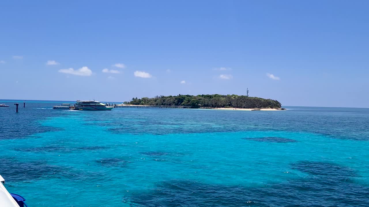 ver pasar el barco atracado en el muelle en una isla verde rodeada de aguas turquesas