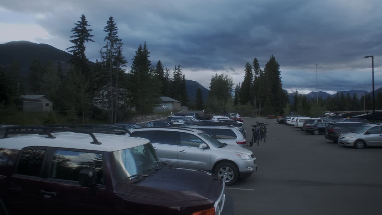 Parking lot in the mountains with Rocky Mountaineer train next to it Banff